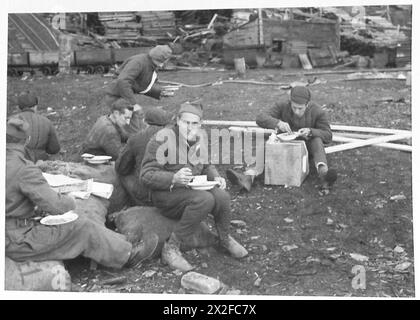 SPITZBERGEN RAID – Freie französische Arbeitsgruppe (immer noch in russischer Polsterung), die sich am Strand eine eilige Mahlzeit schnappt, britische Armee Stockfoto