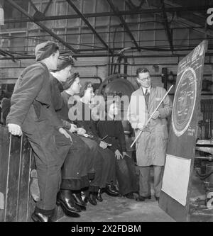 WRENS TRAIN FOR NEW JOB: AUSBILDUNG FÜR SCHIFFSMECHANIKER DES ROYAL MARINEDIENSTES DER FRAUEN, ENGLAND, Vereinigtes Königreich, 1943 - Eine Gruppe von Frauen der WRNS hört einen Vortrag, den ihr Ausbilder über Umbau, Schrumpfung und Defekte verschiedener Holzarten hält, als Teil ihrer Ausbildung zum Schiffsmechaniker (LC), wahrscheinlich im Slough Government Training Centre. Das Diagramm auf der Tafel zeigt einen Teil des Stammes einer Douglasianne und erklärt, wie bestimmte Teile des Baums für bestimmte Arten von Aufgaben am nützlichsten sind Stockfoto