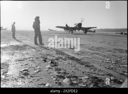 Ein Hawker Typhoon Mark IB der Nr. 143 Wing fährt auf einer eisbedeckten Landebahn in der B78/Eindhoven, Niederlande, vorbei an Supermarine Spitfire Mark IX Stockfoto