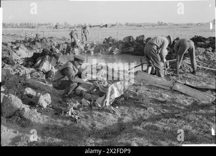 ROYAL AIR FORCE: 2. TAKTISCHE LUFTWAFFE, 1943-1945. - Ein RAF-Offizier untersucht Trümmerteile des ersten deutschen Jets, der von der RAF abgeschossen wurde, während sich die Royal Engineers darauf vorbereiten, Wasser aus dem Krater zu entwässern, der durch seinen Aufprall in einem Feld südwestlich von Nijemegen in Holland hinterlassen wurde, um nach weiteren Überresten zu suchen. Das Flugzeug, eine Messerschmitt ME 262, geflogen von Hauptmann Hans-Christoff Buttman mit 1./KG(J) 51, war am Vortag der Royal Canadian Air Force, 401 Squadron, Royal, einer Patrouille von fünf Supermarine Spitfire Mark IX der No. 401 Squadron RCAF, angeführt von Squadron Leader R I A Smith, gefallen Stockfoto