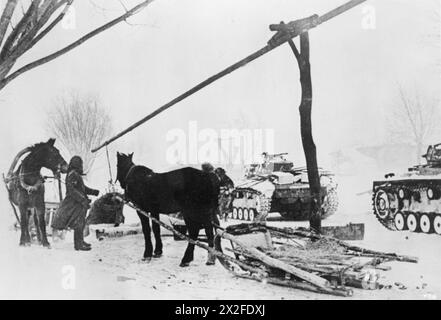Deutsche Soldaten sammeln Wasser aus gefrorenen Quellen, während Panzer III im tiefen Schnee östlich von Kursk im März 1942 an der Ostfront positioniert werden. Stockfoto