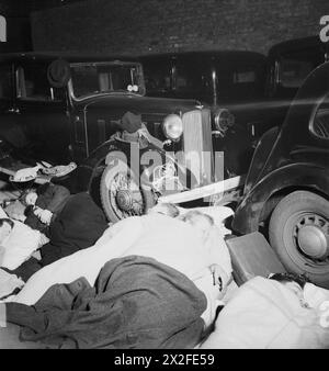 Die Menschen schlafen nachts in einer Garage im Südwesten Londons in Pimlico neben geparkten Autos, fotografiert von Bill Brandt im November 1940 in Schwarz-weiß. Stockfoto