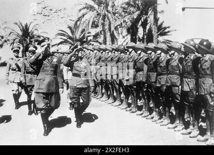 DIE DEUTSCHE ARMEE IM westlichen WÜSTENFELDZUG, 1941-1942 – General Erwin Rommel, Kommandeur des Deutschen Afrika-Korps, inspiziert seine Truppen mit General Garibaldo von Italien kurz nach ihrer Ankunft in Nordafrika, 21.-31. Märsch 1941. Die Truppen tragen Helme der deutschen Armee, der italienischen Armee, Rommel, Erwin Johannes Eugen Stockfoto