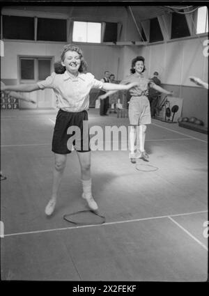 FABRIKWOHLFAHRT: WOHLFAHRT IN PILKINGTON'S GLASFABRIK, ST HELENS, LANCASHIRE, ENGLAND, VEREINIGTES KÖNIGREICH 1944: Frauen machen im Turnsaal im Rehabilitationszentrum der Fabrik (wahrscheinlich in Pilkingtons Glaswerk in St. Helens) Schrittsprünge, um sich nach einer Verletzung zu erholen. Der Originalüberschrift zufolge ist es das Ziel [des Zentrums], Männer und Frauen daran zu hindern, dauerhaft behindert zu werden. Durch Übungen und Massagen unter der Leitung eines in modernen Methoden ausgebildeten Physiotherapeuten erhalten die Verletzten eine Erholungsbehandlung, bis sie die maximale Genesung von ihrer Verletzung erreichen.“ Stockfoto