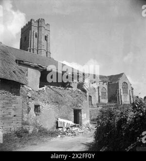 US BATTLE TRAINING AREA, DEVON, ENGLAND, Großbritannien, SEPTEMBER 1944 - Ein Blick auf das stark beschädigte Church House Inn in Stokenham, Devon, das zwar drei Viertel Meilen landeinwärts, aber einen direkten Treffer durch Marineschießen erhielt, die während der Trainingsübungen zur Vorbereitung der D-Day Landung durchgeführt wurden. Die Skyline dominiert die Pfarrkirche St. Michael and All Angels, die unversehrt blieb Stockfoto