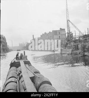 BRITISCHE KANÄLE IN KRIEGSZEITEN: TRANSPORT IN GROSSBRITANNIEN, 1944 - zwei kleine Kinder fahren auf dem „Deck“ eines Kanalbootes mit Fruchtfleischfässern entlang des Regent's Canal in London. Der Zellstoff wird von einem Schiff in der Themse entlang des Regent's Canal und dann über den Grand Union Canal in die Midlands transportiert. Auf der rechten Seite des Fotos sind Schäden, die durch einen früheren Luftangriff verursacht wurden, deutlich am Ufer des Kanals zu sehen Stockfoto