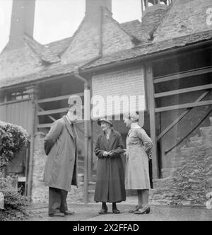 Vor den Hugh Perry Almshouses in Wotton-under-Edge, Gloucestershire, spricht Mr. Ford, Vorsitzender der General Charitys, mit der 90-jährigen Mrs. Harding, der ältesten Assistentin, und Mrs. Hayward, der Matron. Die Almshouses wurden 1638 gegründet und bieten Platz für 29 Personen. Stockfoto