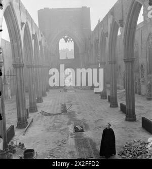 Eine KIRCHE ERHEBT SICH AUS DER ASCHE: BOMBENSCHADEN AN DER St GEORGE's CATHEDRAL, SOUTHWARK, 1942 – Ein Priester, wahrscheinlich Pater Dixon, steht in der dachlosen Hülle der St George's Roman Catholic Cathedral, an der Ecke St George's Road und Lambeth Road in Southwark, South East London. Die Kathedrale wurde durch einen Brandbombenangriff am 16. April 1941 schwer beschädigt. Das Foto wurde vom Altarende des Gebäudes aufgenommen und blickt zurück zum Kirchenschiff in Richtung Tür Stockfoto