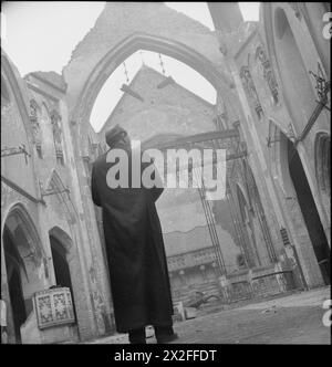 EINE KIRCHE ERHEBT SICH AUS DER ASCHE: BOMBENSCHADEN AN DER St. GEORGE's CATHEDRAL, SOUTHWARK, 1942 - Pater Frederick Dixon untersucht die Schäden, während er auf den Altar der St. George's Roman Catholic Cathedral blickt, an der Ecke St George's Road und Lambeth Road in Southwark, South East London. Die Kathedrale ist heute eine dachlose Hülle, nachdem am 16. April 1941 ein Brandbombenangriff auf das Gebäude ausgerottet wurde Stockfoto