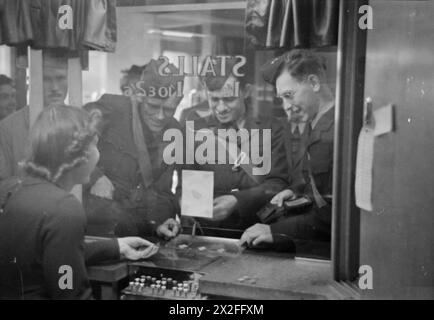 AMERIKANER IN GROSSBRITANNIEN: DIE ANKUNFT DES ZIVILEN TECHNISCHEN KORPS, BOURNEMOUTH, ENGLAND, 1941 – Manning, Henning und Shapiro des zivilen technischen Korps kaufen Tickets im Kino in Bournemouth. Das Foto wird vom Ticketschalter aus aufgenommen und hinter ihnen bildet sich eine Warteschlange. Die Männer stammen ursprünglich aus Del Rio, Texas, Champaign, Illinois und Chicago Stockfoto