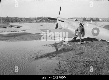 Ein fotografischer Aufklärungspilot der No. 400 Squadron RCAF besteigt eine Supermarine Spitfire PR Mark XI bei B78/Eindhoven, Holland, inmitten von Wasser der jüngsten schweren Regenfälle in den Jahren 1943–1945. Stockfoto