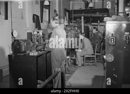 NATIONALES PHYSISCHES LABOR: WISSENSCHAFT UND TECHNOLOGIE IN KRIEGSZEITEN, TEDDINGTON, MIDDLESEX, ENGLAND, VEREINIGTES KÖNIGREICH, 1944: Eine Szene in der Schiffsforschungsabteilung des National Physical Laboratory in Teddington, in der Wissenschaftler die Auswirkungen von Kräften auf einen Modellpropeller untersuchen. Der Fahrer, der in der Mitte sitzt, blickt durch das Sichtfenster des Oberarms des Drucktunnels Lithgow. Die Originalunterschrift besagt, dass das Wasser in diesem Teil des Kreislaufsystems mit kontrollierter Geschwindigkeit und unter kontrolliertem Druck in Bewegung ist. Der zu prüfende Propeller ist angeschlossen Stockfoto