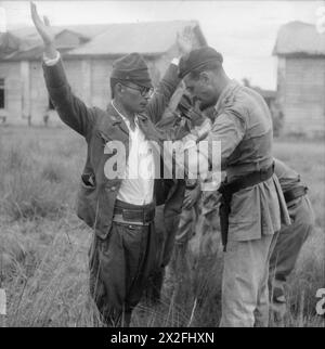 1945: Ein japanischer Offizier, der sich gerade ergeben hat, wird von einem Offizier der 3. Commando Brigade der Royal Navy, 3. Royal Marine Commando Brigade, durchsucht Stockfoto