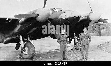 KÖNIGLICHE LUFTWAFFE, 1942-1945. - Wing Commander F W Hillock, Offizierskommandant Nr. 410 Geschwader RCAF (links), und Flight Lieutenant P O'Neill-Dunne (rechts), vor ihrem de Havilland Mosquito NF Mark II in Coleby Gange, Lincolnshire, mit 300 Fuß Kupfer-Funkkabel, das sie zurückbrachten, umwickelt um das Flugzeug von einem Eindringling über Holland. In der Nacht vom 15. April 1943 führten Hillock (Pilot) und O’Neill-Dunne (Beobachter) einen Nachtläufer ins Ruhrtal ein. Beim Flug auf niedrigem Niveau bei schlechtem Wetter wurden sie plötzlich mit t konfrontiert Stockfoto