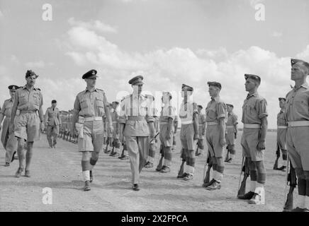 ROYAL AIR FORCE OPERATIONEN IM NAHEN OSTEN UND NORDAFRIKA, 1939-1943. - König Georg VI. Inspiziert eine Ehrenwache des RAF-Regiments bei seiner Ankunft in Hammamet, Tunesien, während seines Besuchs in Nordafrika. Die große Figur auf der linken Seite ist Air Commodore L F Sinclair, Air Officer, der die Taktische Bombertruppe der Nordwest-Alliierten Taktischen Luftwaffe kommandiert. Zu seiner Rechten, in der Ferne, Sir Arthur Tedder, Oberbefehlshaber des Mittelmeer-Luftkommandos, geht entlang der Linie der Flieger George VI, King, Royal Air Force, Royal Air Force Regiment Stockfoto