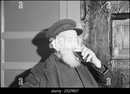 HOLY ISLAND SPIELT SEINE ROLLE: ALLTAG AUF LINDISFARNE, 1942 - ein älterer Fischer genießt ein Bier im Crown and Anchor Public House auf Lindisfarne Stockfoto