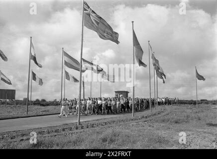 DAS FERIENLAGER GEHT WIEDER LOS: DER ALLTAG IN EINEM BUTLIN'S FERIENLAGER, FILEY, YORKSHIRE, ENGLAND, GROSSBRITANNIEN, 1945: unter der Leitung eines Trainers für körperliches Training marschieren Camper im Butlin's Holiday Camp, Filey, durch den fahnengesäumten Eingang zum Camp während einer der täglichen PT-Sitzungen am frühen Morgen, die vom Camp durchgeführt werden Stockfoto