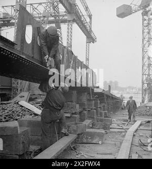 MÄNNER UND FRAUEN HINTER GROSSBRITANNIENS SCHIFFEN. MAI 1945, YARGARS MARINESCHIFT, GLASGOW. - Männer bei der Arbeit, die auf dem Kiel eines Zerstörers Yarrow & Company Limited, Glasgow, Schiffbauer nieten Stockfoto