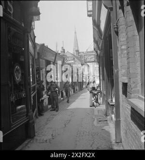 GUILDFORD: DER ALLTAG IN DER KRIEGSZEIT GUILDFORD, SURREY, ENGLAND, 1945 - Ein Blick auf die Swan Lane in Guildford. Auf der linken Straßenseite befinden sich Optiker von Salisbury und Son, Stationäre von Dowdeswells, eine Reinigungsfirma und ein Chiropodist. Rechts sehen Sie einen Tabakladen und einen Herrenfriseur-Salon Stockfoto