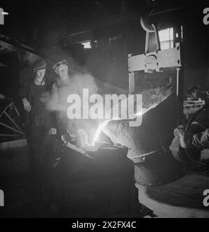 MÄNNER UND FRAUEN HINTER GROSSBRITANNIENS SCHIFFEN. MAI 1945, ALSTON FOUNDRY, ALSTON, CUMBERLAND. - Geschmolzener Stahl wird in eine Gliederform gegossen, Alston Foundry Stockfoto