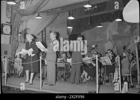Tommy Handley stellt dem Publikum die Sängerin Ann Rich bei der 1945 Aufnahme der Radiokomödie IT's That man Again vor, bei der Charlie Shadwell das BBC Variety Orchestra dirigiert. Stockfoto