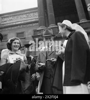 HARRY HARGREAVES GEHT NACH BUCKINGHAM PALACE: VON YORKSHIRE NACH LONDON, UM SEINE BRITISH EMPIRE-MEDAILLE 1943 zu SAMMELN, nachdem er seine British Empire-Medaille erhalten hatte, spricht Harry Hargreaves, BEM, mit Krankenschwestern und einem Seemann vor dem Buckingham Palace. Alle wurden vom König dekoriert und vergleichen Medaillen miteinander Stockfoto