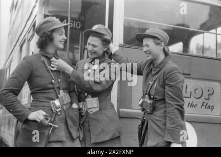 LONDON BUSES IN KRIEGSZEITEN, ENGLAND, 1941 – die Londoner Busleiter Lilian Menhenett, Louise Taylor und Marie Ellis teilen sich einen Witz, als sie nach ihrer Schicht ihren Dienst verlassen. Dieses Foto wurde wahrscheinlich im September 1941 aufgenommen Stockfoto