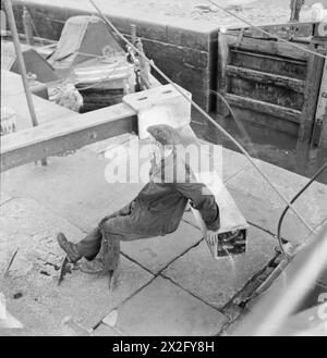 BRITISH CANALS IN WARTIME: TRANSPORT IN BRITAIN, 1944 – Ein Bootsmann öffnet ein Schleusentor, irgendwo am Grand Union Canal Stockfoto