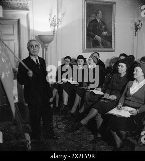 BRITEN LERNEN TÜRKISCH: ERWACHSENENBILDUNG IN LONDON, 1943 - Bay Ali Riza Sencan, Sekretär der Halkevi, zeigt auf die Tafel, während er die Klasse über die drei verschiedenen Pronomen-Suffixe unterrichtet. Die erste Reihe der Klasse hört ihm aufmerksam zu. Ein Porträt von Kemal Atatürk ist an der Wand hinter ihnen zu sehen. Zweimal pro Woche finden hier Türkisch-Sprachkurse statt Stockfoto