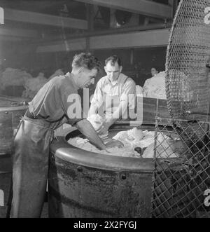 WÄSCHEREI IN KRIEGSZEITEN: DIE ARBEIT VON GLENIFFER WÄSCHEREI, CATFORD, LONDON, ENGLAND, UK, 1944 – in der Gleniffer Laundry in Catford laden Arbeiter den Wasserabsauger, der einen Großteil des Wassers aus frisch gewaschenen Gegenständen entfernt. Der Originaltitel besagt, dass „es die Version der Wäscherei ist“ Stockfoto