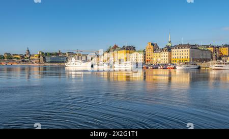 Boote ankern in den ruhigen Gewässern des Stockholmer Hafens unter einem klaren blauen Himmel, mit der historischen Architektur der Stadt am Ufer. Stockholm, Schweden Stockfoto