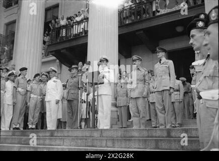 UNTERZEICHNUNG DER KAPITULATION JAPANS IN SINGAPUR, 1945 - Admiral Lord Louis Mountbatten hält während der Kapitulationszeremonie eine öffentliche Ansprache von den Stufen der Stadtgebäude in Singapur. Links von Mountbatten befinden sich Admiral Power und Lieutenant General Slim und rechts Lieutenant General Wheeler und Air Chief Marshal Sir Keith Park Mountbatten, Louis Francis Albert Victor Nicholas George, Power, Arthur John, Slim, William Joseph, Wheeler, Raymond Albert, Park, Keith Rodney Stockfoto