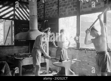 MIT DER FLOTTENLUFTWAFFE IM OSTEN. ROYAL MARINEFLUGSTATION KATAKURUNDA, CEYLON. TÄTIGKEITEN DES FLOTTENFLUGWAFFENBODENPERSONALS IN DEN TROPEN. - In den Tropen verlangt der Schmied gute körperliche Fitness und Ausdauer. Hier rundet ein Schmied, bis an die Taille gestreift, eine Autoachse ab Stockfoto