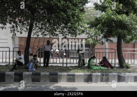 22. April 2024: Menschen sitzen auf dem Straßentrenner unter Bäumen, um sich vor der landesweit andauernden Hitzewelle in Dhaka, Bangladesch, am 22. April 2024 zu schützen. (Kreditbild: © Anik Rahman/ZUMA Press Wire) NUR REDAKTIONELLE VERWENDUNG! Nicht für kommerzielle ZWECKE! Stockfoto