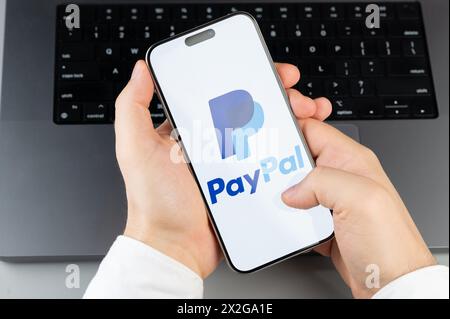 New York, USA - 6. April 2024: Beliebte Paypal Mobile App auf Smartphone-Bildschirm in Händen auf Laptop-Tastatur Hintergrund Stockfoto