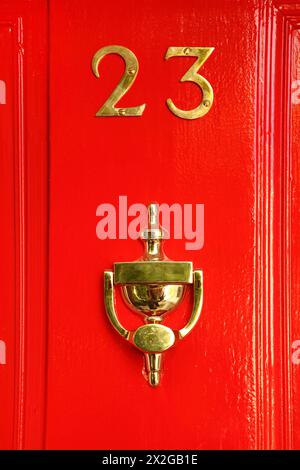 goldenes Schild an roter Holztür; 23 und Tasse; Reflexion im Becher Stockfoto