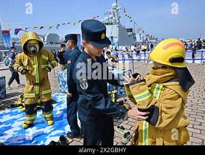 (240422) -- QINGDAO, 22. April 2024 (Xinhua) -- Besucher probieren feuerfeste Anzüge am Pier 3 im Qingdao Hafen von Qingdao, ostchinesische Provinz Shandong, 21. April 2024. Die chinesische Volksbefreiungsarmee Navy hält um den 23. April in mehreren Küstenstädten, darunter Qingdao, Open Day Events ab, um den 75. Jahrestag ihrer Gründung zu feiern. Vom 20. Bis 24. April kann die Öffentlichkeit in Qingdao die Raketenzerstörer Guiyang, Shijiazhuang und Kaifeng, die Raketenfregatte Handan, das Versorgungsschiff Kekexilihu und das U-Boot Hongzehu am Pier 3 und die Qingdao International Sailin besichtigen Stockfoto