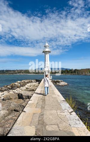 Genf, Schweiz - 5. April 2024: Eine junge Frau spaziert entlang des Piers in Richtung des Leuchtturms Paquis am Genfer See Stockfoto