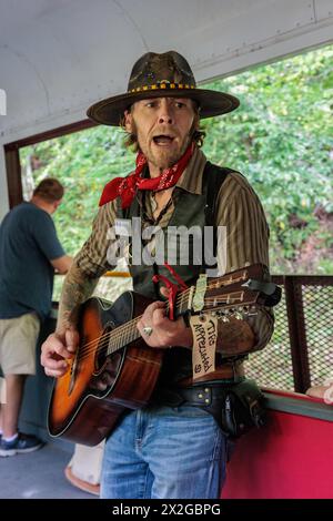 Sänger und Entertainer reisen von Auto zu Auto und singen Lieder zu den Passagieren, um Tipps für den Ausflug mit der Great Smoky Mountains Railroad ab Bryson CI zu erhalten Stockfoto