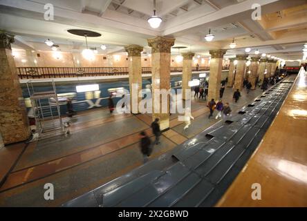 Leute, die in die U-Bahn gehen, weiße Marmorsäulen, blaue Bahn Stockfoto