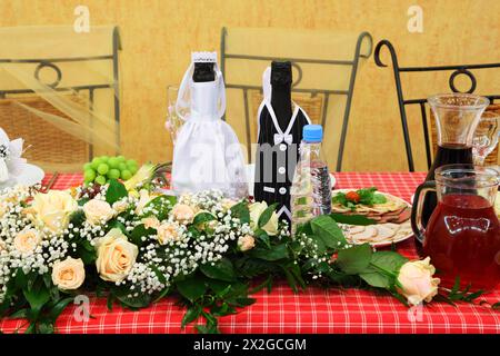 Flaschen Champagner in Hochzeitskleidern stehen auf festlichem Tisch Stockfoto