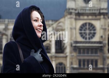 Junge lächelnde Frau Nahaufnahme auf dem Hintergrund von Eglise Saint-Eustache in Paris. Kathedrale in geringer Tiefe. Stockfoto