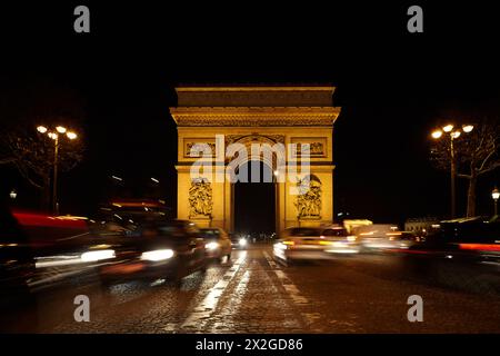 Triumphbogen auf dem SDG-Platz bei Nacht. Der Weg ist unfokussiert. Verschwommene Lichtspuren von Autos. Stockfoto