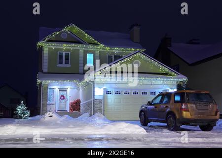 Am Abend stehen neben dem Haus dekorierte Girlanden-Maschine und zwei Fichten an weihnachten Stockfoto