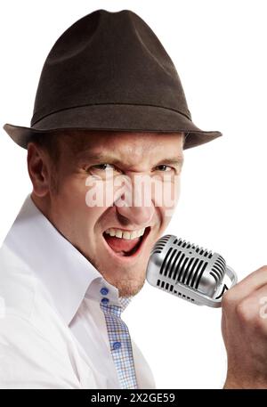 Der Mann mit dem braunen Filzhut singt ausdrucksvoll ins Mikrofon. Stockfoto