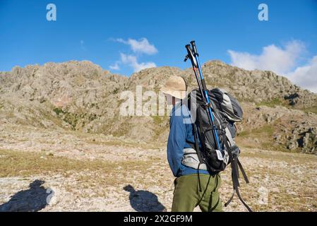 Hispanischer Wanderer, der mit seinem Rucksack unterwegs ist, wo er seine Trekkingstöcke befestigt hat, bereit für den Beginn der Wanderung. Los Gigantes, in Cordoba, Argentinien. Stockfoto