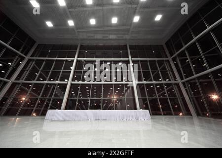 Tisch mit weißer Tischdecke in großer, geräumiger, leerer Lobby Stockfoto