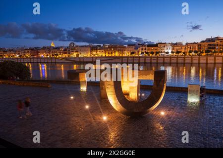 Sevilla, Spanien - 23. Oktober 2023 - Denkmal der Toleranz (Monumento a la Tolerancia) und Skyline des Triana-Viertels am Guadalquivir-Fluss bei Nacht. Stockfoto