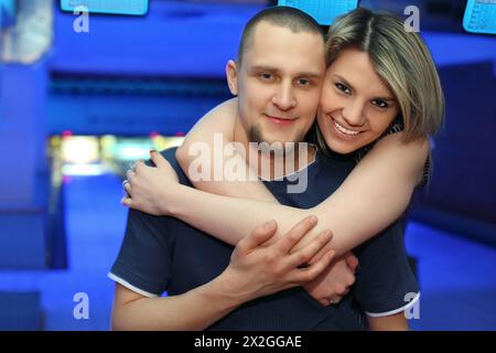 Das Mädchen umarmt den Mann und lächelt während der Ruhe im Bowling des Clubs Stockfoto