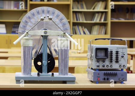 Der alte Wimshurst beeinflusst Machin und pädagogisches Oszilloskop auf dem Schreibtisch in leerem Physikunterricht Stockfoto